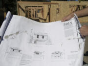 Dmitriy Manzhura of Vast Homes looks over plans for an accessory dwelling unit as the main building is seen in the background Monday morning.