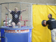 Vancouver Police Department Lt. Steve Neal, right, pushes the target Thursday to dunk Jenny Thompson, the executive director for the Vancouver Police Activities League, into the water at Mill Creek Pub in Battle Ground during Give More 24!