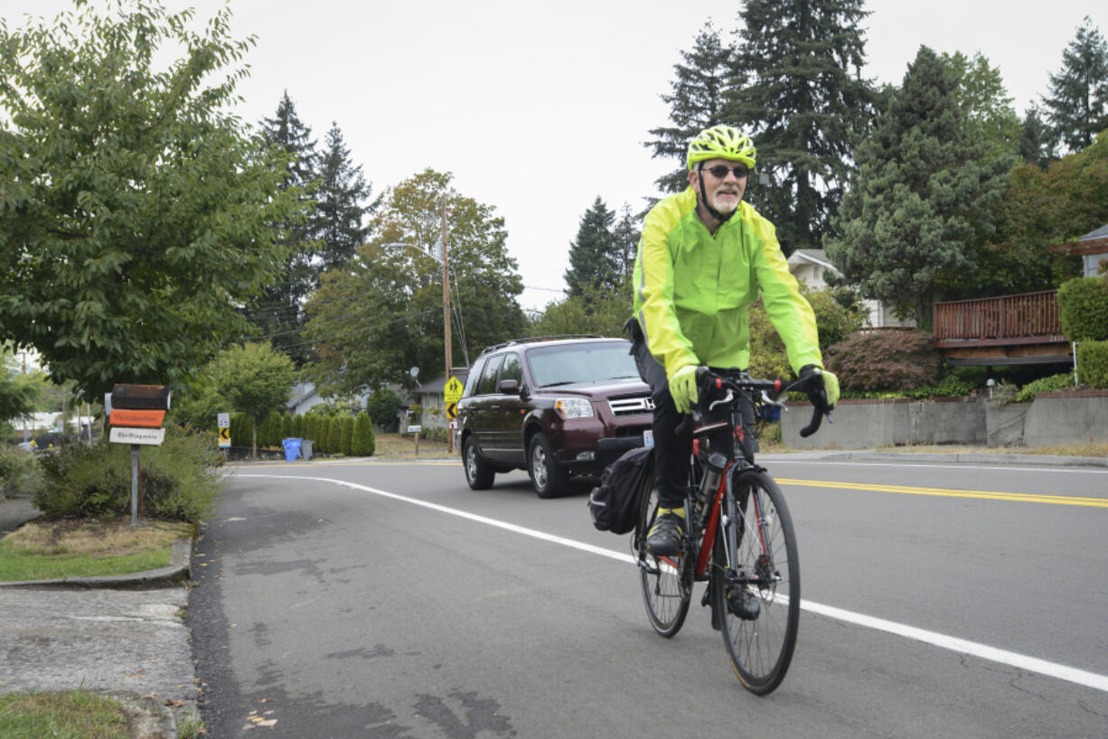 Jim Thomas rides his bicycle up the steep hill of East McLoughlin Boulevard, just past the X Street intersection, as a car passes him Sept. 6. Residents in the Central Park neighborhood and members of a local bicycle stakeholders group have proposed a project to install speed radar signs and eliminate on-street parking on the south side of East McLoughlin for an eastbound bike lane.