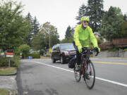 Jim Thomas rides his bicycle up the steep hill of East McLoughlin Boulevard, just past the X Street intersection, as a car passes him Sept. 6. Residents in the Central Park neighborhood and members of a local bicycle stakeholders group have proposed a project to install speed radar signs and eliminate on-street parking on the south side of East McLoughlin for an eastbound bike lane.