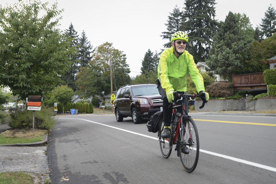 Jim Thomas rides his bicycle up the steep hill of East McLoughlin Boulevard, just past the X Street intersection, as a car passes him Sept. 6. Residents in the Central Park neighborhood and members of a local bicycle stakeholders group have proposed a project to install speed radar signs and eliminate on-street parking on the south side of East McLoughlin for an eastbound bike lane.