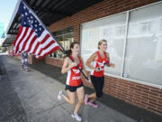 Marcelle Abel, holding the flag, and Lyndsey Lanphere run Tuesday morning down Columbia Street in Vancouver to the entrance of the Clark County Veterans Assistance Center, completing their leg in the Old Glory Relay.