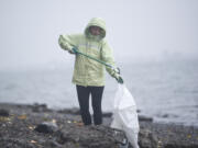 Christina Hubbard of Vancouver drops trash into a bag during a waterfront cleanup event Saturday morning along the Columbia River Waterfront Renaissance Trail in Vancouver. The effort was organized by SOLVE Oregon and the Fort Vancouver National Historic Site.