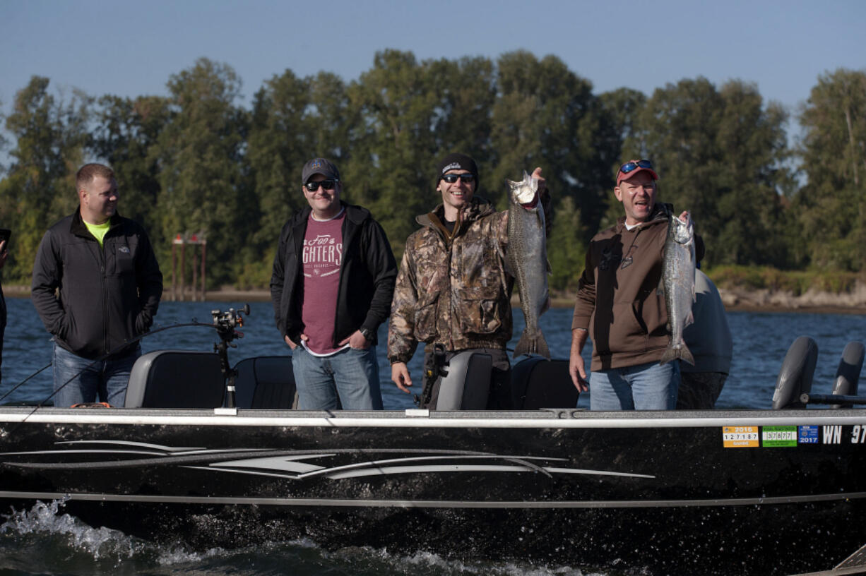 Baton Rouge police Officer Taylor Giroir, from left, Clark County sheriff's Deputy Jared Stevens, Battle Ground police Officer Slav Pavlenko and Baton Rouge police Cpl. Britt Jones celebrate their catch Monday morning. The group was one of a dozen that took to the Columbia River as part of a law enforcement appreciation event.