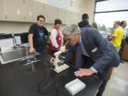 Gary Gilliland, president of the Fred Hutchinson Cancer Research Center in Seattle, looks at a slide of Shigella dysenteriae under a microscope during a tour of Henrietta Lacks Health and Bioscience High School on Monday morning.