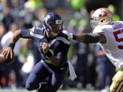 Seattle Seahawks quarterback Russell Wilson, left, scrambles away from San Francisco 49ers' Ahmad Brooks in the first half of an NFL football game, Sunday, Sept. 25, 2016, in Seattle.