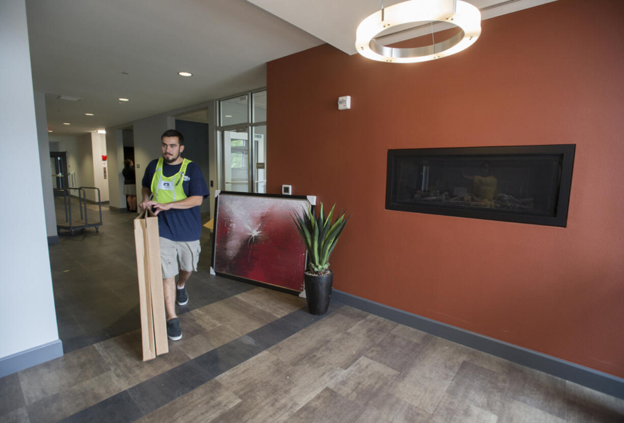 Jose Tomas of O&#039;Neill Transfer &amp; Storage Co. brings a piece of artwork into a community space Wednesday in Freedom&#039;s Path at Vancouver, a residence for veterans in need.