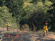 Firefighters tend to a roughly 1-acre field fire Tuesday near Woodland.