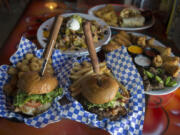 A hula burger, clockwise from bottom left, is served with a plate of tachos, a fajita wrap with chicken, a selection of appetizers and a blue cheese burger at Charlie&#039;s Sports Bar and Grill in Vancouver.