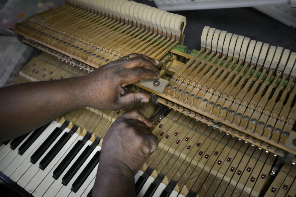 Leal Sylvester, a 1997 graduate and now the new director of instruction intern at the Piano Hospital in Vancouver, works on adjusting the hammer blow distance on a piano.