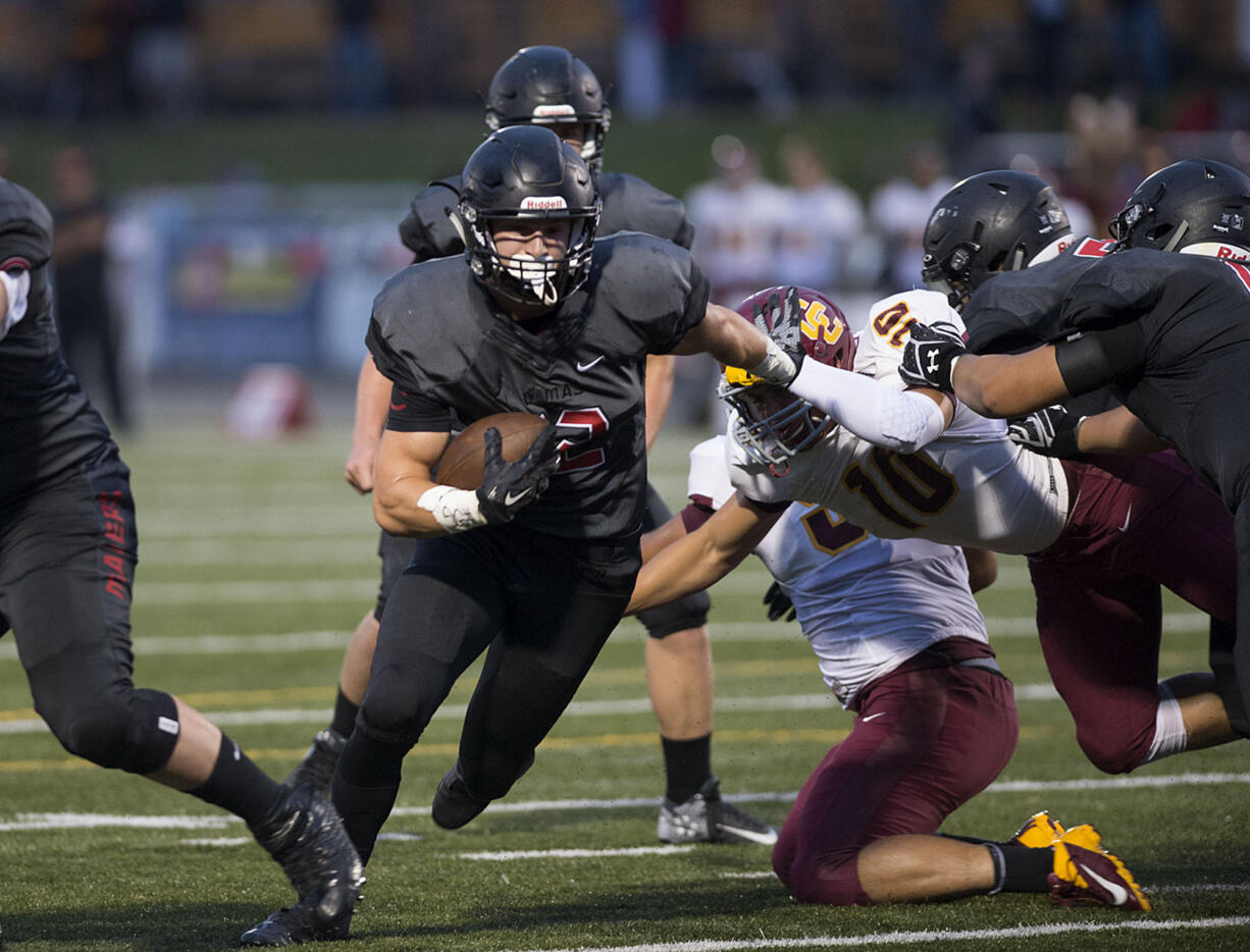 Camas' Michael Matthews (12) scrambles for yardage while defended by Central Catholic's Michael Abraham (10) in the first quarter Friday night, Sept. 2, 2016 at Doc Harris Stadium.