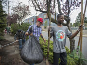 Share House resident Ivan Hand, center, clears leaves and debris during a neighborhood cleanup with fellow resident Nelson Powell, right, on Thursday afternoon.