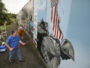 Volunteers Les Mischke, front to back, Jerry Rolling and Terry Ogle work together to remove black mold and dirt from patriotic murals Wednesday morning in downtown Vancouver.