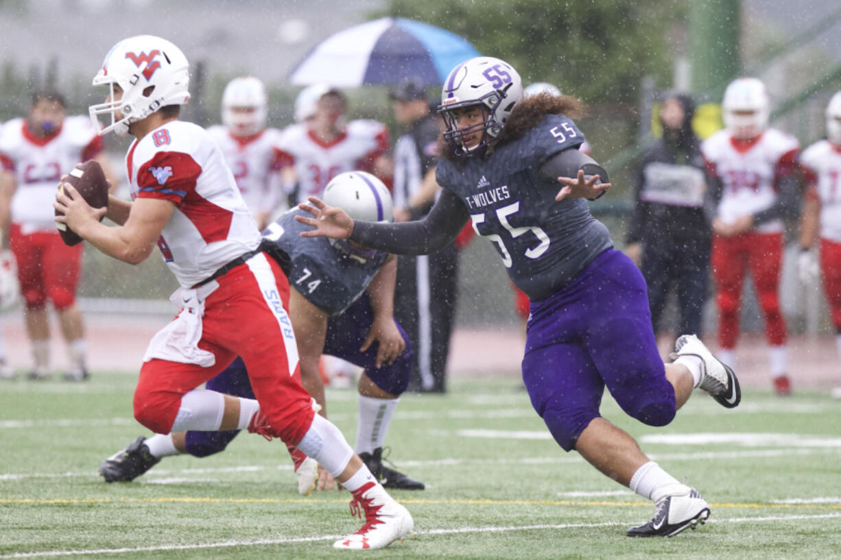 Heritage defensive lineman White Sosene (55) chases West Valley quarterback Brandon Battle (8) at McKenzie Stadium.