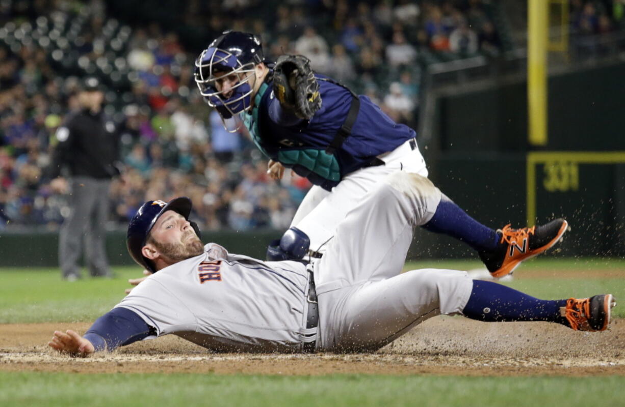 Houston Astros&#039; Tyler White slides safely across home as Seattle Mariners catcher Mike Zunino follows through on a tag during the sixth inning. White and Teoscar Hernandez scored on a single by Yulieski Gurriel on the play.