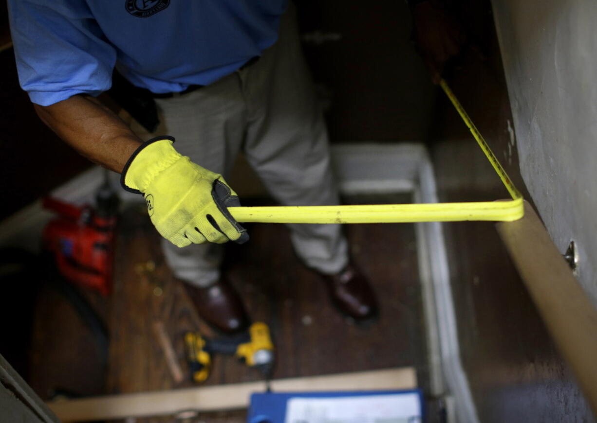 FILE - In this June 12, 2013 file photo, a construction worker takes a measurement while installing a banister in a staircase in a home in Baltimore. Where you live plays a big role in staying independent as you age. Now researchers say an innovative program that combined home fix-ups and visits from occupational therapists and nurses improved low-income seniors&#039; ability to care for themselves in their own homes.