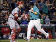 Seattle Mariners' Dae-Ho Lee scores as Los Angeles Angels catcher Jett Bandy waits for the ball Friday night.