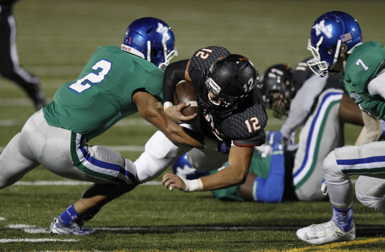 Battle Ground running back Curtis Stradley (12) runs ball against Mountain View defenders Preston Jones (2) and Troy Pacheco (7) at 4A GSHL football league tiebreaker between Skyview, Battle Ground, Mountain View.