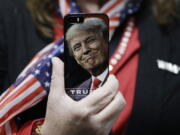 A woman holds up her cellphone Thursday before a rally with Republican presidential candidate Donald Trump in Bedford, N.H.