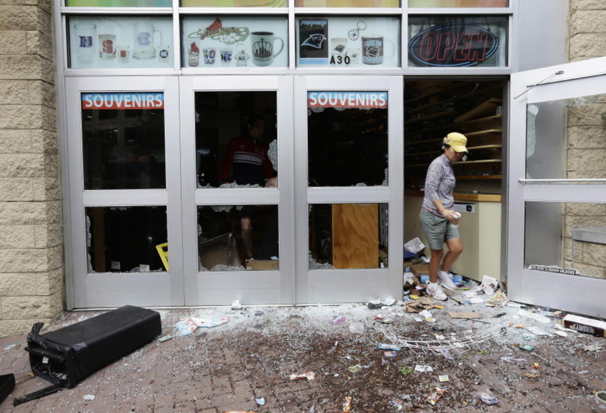 A woman emerges from a storefront following damage from overnight protests stemming from Tuesday&#039;s police shooting of Keith Lamont Scott in Charlotte, N.C., on Thursday.