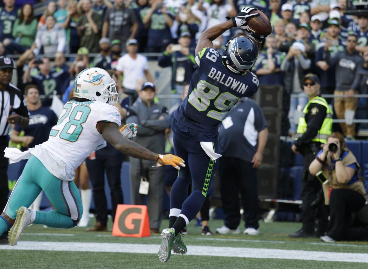 Seattle Seahawks wide receiver Doug Baldwin (89) catches a pass for a touchdown over Miami Dolphins cornerback Bobby McCain (28) in the second half of an NFL football game, Sunday, Sept. 11, 2016, in Seattle.