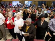 People rise and begin singing during the Guilford County Board of Elections meeting at the Old Guilford County Courthouse in Greensboro, N.C. The swing state of North Carolina could be pushed in a Republican or Democratic direction when the GOP-led State Board of Elections meets Thursday to finalize early voting plans for a third of the state&#039;s counties.