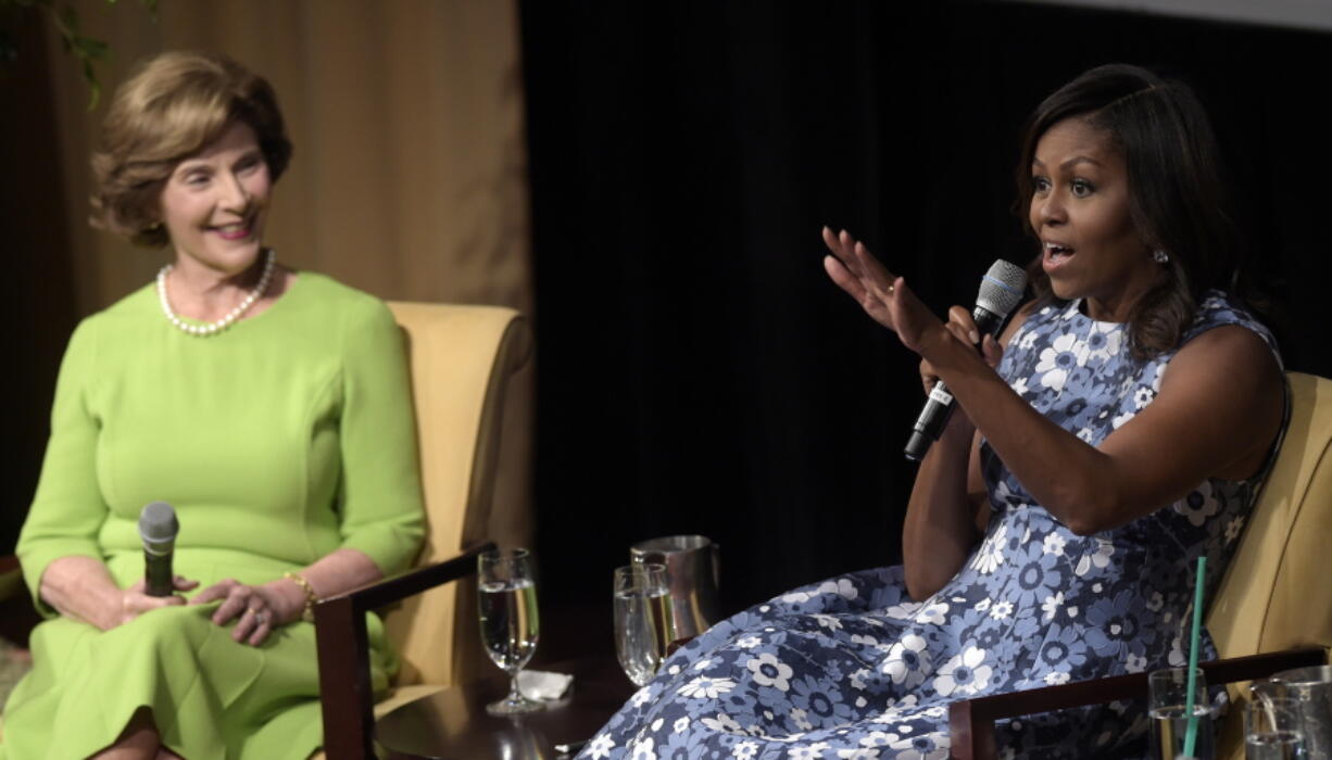 First lady Michelle Obama, accompanied by former first lady Laura Bush, speaks Friday during the &quot;America&#039;s First Ladies: In Service to Our Nation&quot; conference at the National Archives in Washington. Obama will appear at her first campaign rally for Hillary Clinton on Friday in northern Virginia.