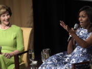 First lady Michelle Obama, accompanied by former first lady Laura Bush, speaks Friday during the &quot;America&#039;s First Ladies: In Service to Our Nation&quot; conference at the National Archives in Washington. Obama will appear at her first campaign rally for Hillary Clinton on Friday in northern Virginia.