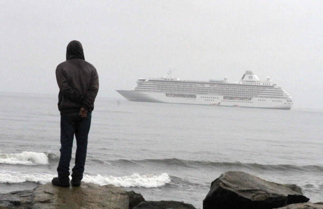 A man stands Aug. 21 on the Bering Sea shore looking at the luxury cruise ship Crystal Serenity anchored just outside Nome, Alaska. The ship made a port call as it became the largest cruise ship to ever go through the Northwest Passage, en route to New York City.