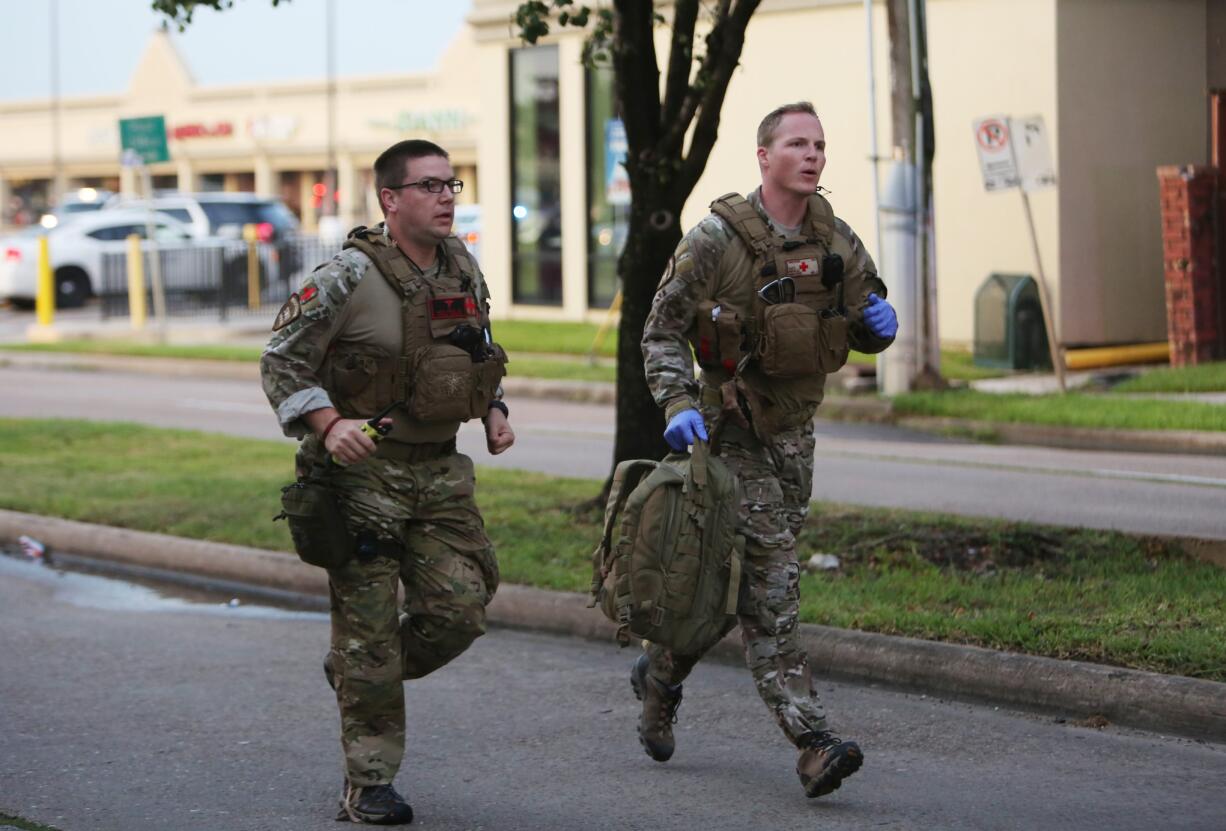 Law enforcement officers run toward the scene of a shooting along Wesleyan at Law Street in Houston that left multiple people injured and the alleged shooter dead, Monday morning, Sept. 26, 2016.