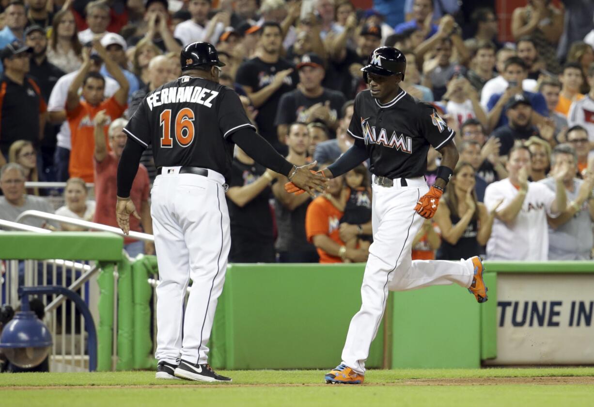 Miami Marlins Dee Gordon, right, shakes hands with third base coach Lenny Harris, left, after he hit a solo home run during the first inning in a baseball game against the New York Mets, Monday, Sept. 26, 2016, in Miami.