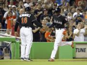 Miami Marlins Dee Gordon, right, shakes hands with third base coach Lenny Harris, left, after he hit a solo home run during the first inning in a baseball game against the New York Mets, Monday, Sept. 26, 2016, in Miami.