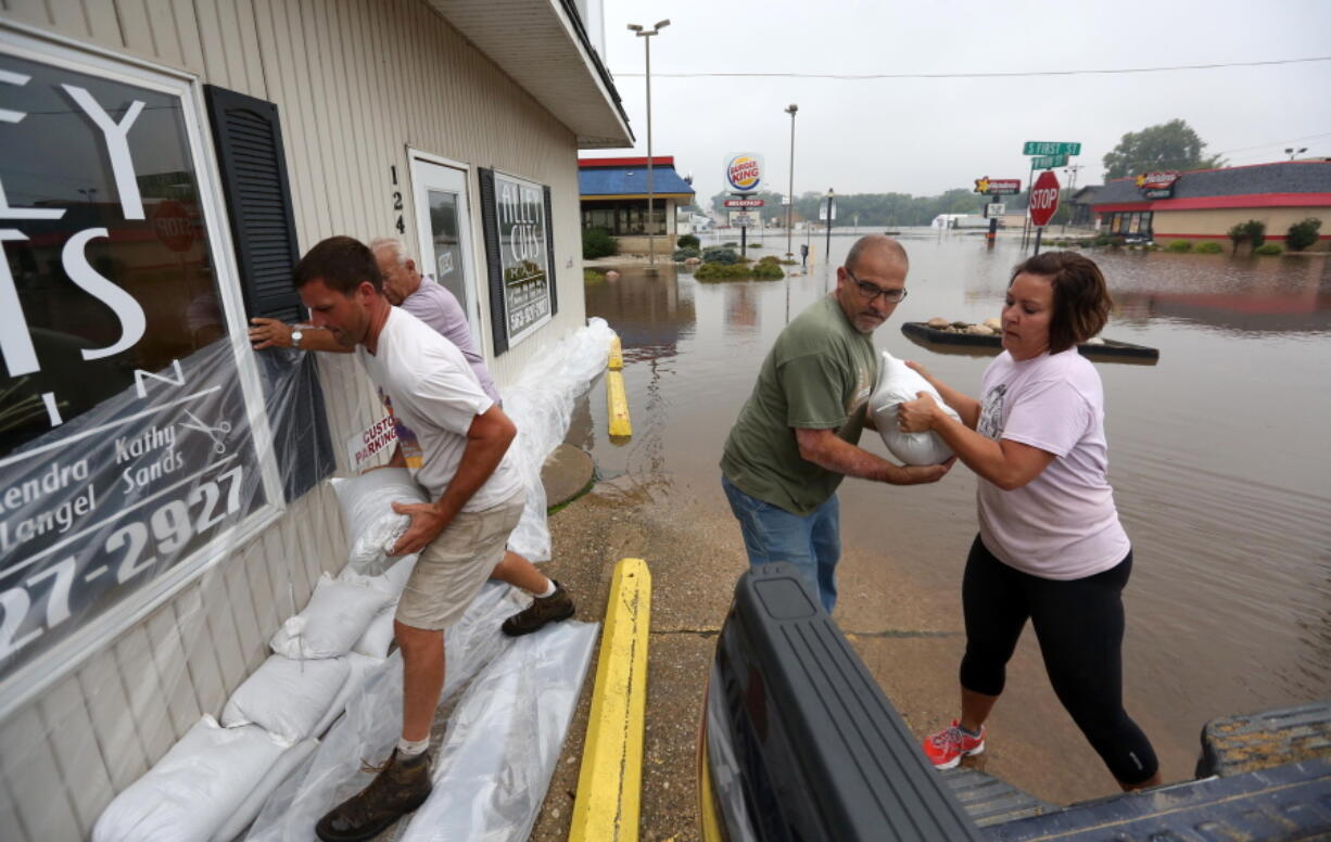 Holly Cole, right, and Michael Ridenou, second from right, work to build sandbag walls at the Alley Cuts shop Fridayin Manchester, Iowa. Authorities in several Iowa cities were mobilizing resources Friday to handle flooding from a rain-swollen river that has forced evacuations in several communities upstream.