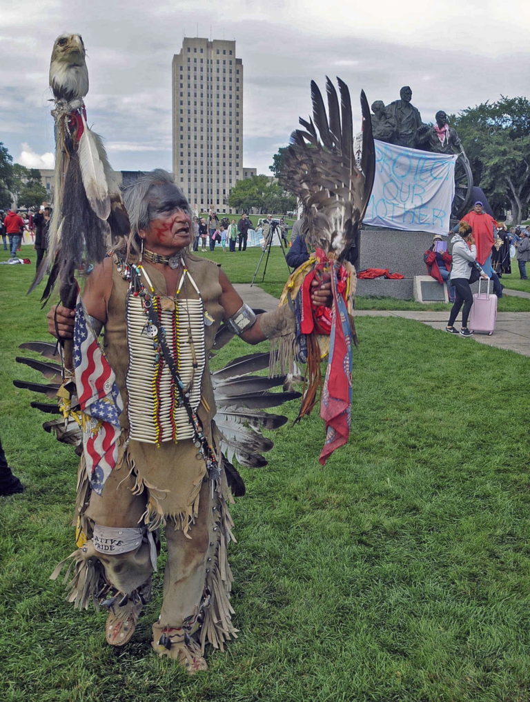 Phil Little Thunder, of Rosebud, S.D. shows his support during the protest on the grounds of the North Dakota state capitol in his pow wow regalia, Friday, Sept. 9, 2016 in Bismarck, N.D. The federal government stepped into the fight over the Dakota Access oil pipeline Friday, ordering work to stop on one segment of the project in North Dakota and asking the Texas-based company building it to "voluntarily pause" action on a wider span that an American Indian tribe says holds sacred artifacts.