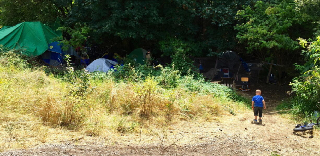 A boy walks into a homeless encampment along the Springwater Corridor bike and pedestrian trail n August in Portland.