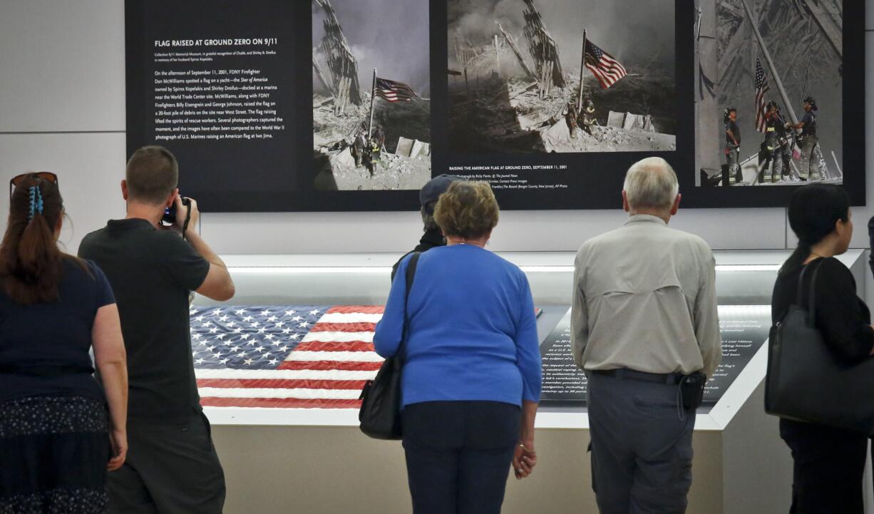 Visitors view the display for the American flag, left, that firefighters hoisted at ground zero in the hours after the 9/11 terror attacks, Thursday Sept. 8, 2016, at the Sept. 11 museum in New York. After disappearing for more than a decade the 3-foot-by 5-foot flag was donated to the museum after it was turned in two years ago by an as-yet-unidentified man at a firehouse in Everett, Wash.