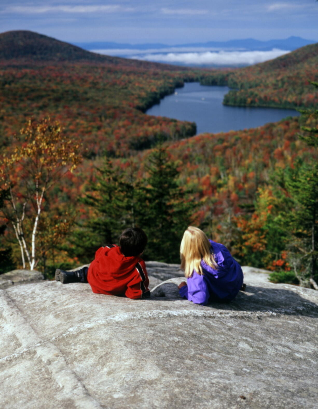 People take in the fall foliage from Owls Head Mountain in Groton State Forest in Vermont. Kettle Pond is seen in the distance.