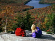 People take in the fall foliage from Owls Head Mountain in Groton State Forest in Vermont. Kettle Pond is seen in the distance.