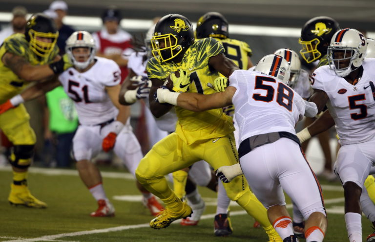 Oregon's Royce Freeman, center, is tackled by Virginia's Eli Hanback during the first quarter an NCAA college football game Saturday, Sept. 10, 2016 in Eugene, Ore.