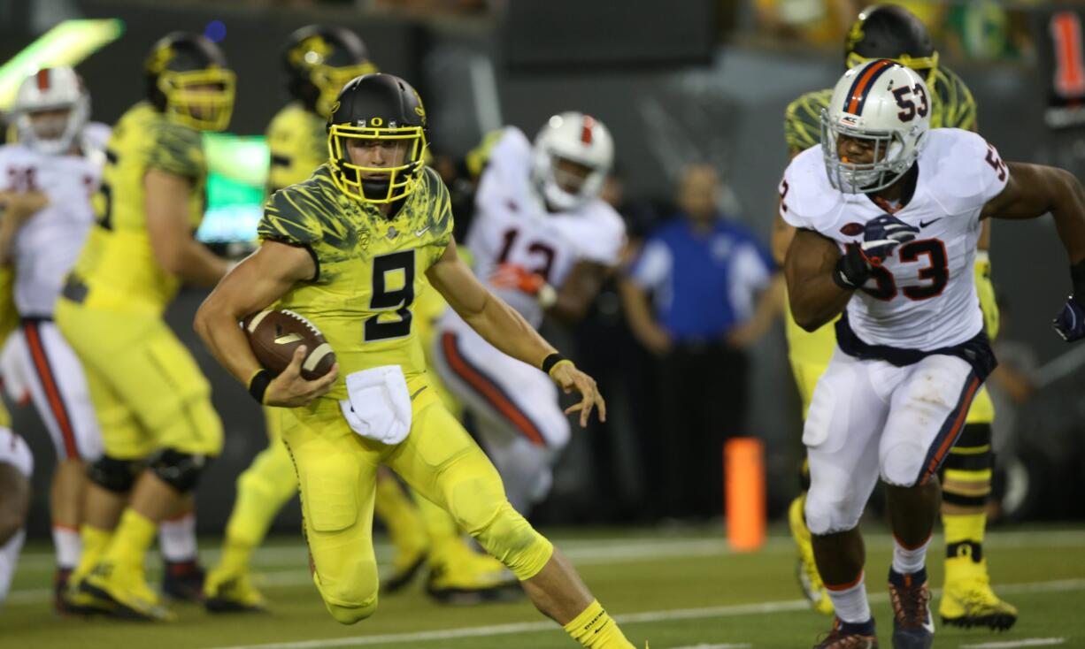 Oregon quarterback Dakota Prukop, left, evaded defensive pressure from Virginia's Mich Kiser, right, during the second quarter of an NCAA college football game Saturday, Sept. 10, 2016 in Eugene, Ore.