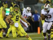 Oregon quarterback Dakota Prukop, left, evaded defensive pressure from Virginia's Mich Kiser, right, during the second quarter of an NCAA college football game Saturday, Sept. 10, 2016 in Eugene, Ore.