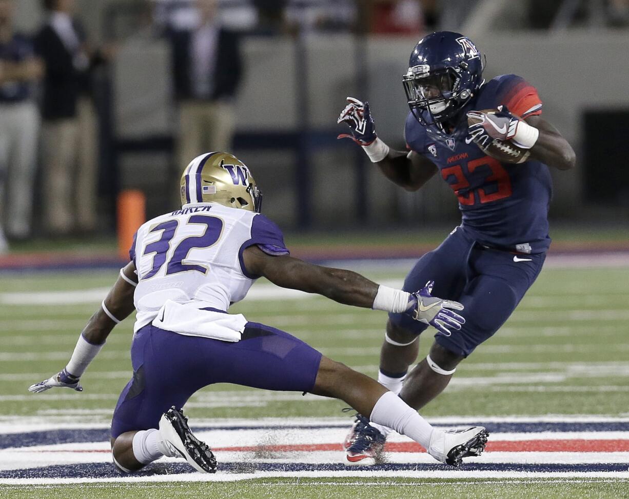 Arizona running back J.J. Taylor (23) avoids Washington defensive back Budda Baker during the first half of an NCAA college football game, Saturday, Sept. 24, 2016, in Tucson, Ariz.