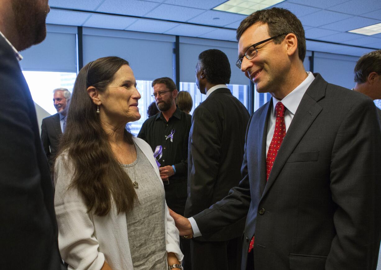 After a press conference in Seattle regarding legislation that would  ban assault weapons in Washington state, Washington State Attorney General Bob Ferguson, right, speaks with Dr. Liz Raemont, mother of Will Kramer who survived a shooting in Mukilteo, Wash., where three young people were killed.  (Ellen M.