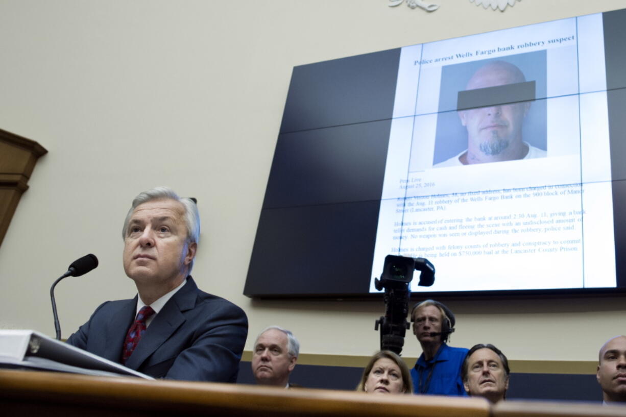 A police press release pertaining to the arrest of Robert Holmes, who was charged with robbing a Wells Fargo Bank in Lancaster, Pa., is projected behind Wells Fargo CEO John Stumpf on Capitol Hill in Washington on Thursday as he testifies before the House Financial Services Committee investigating Wells Fargo&#039;s opening of unauthorized customer accounts.