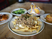 Pulled-pork poutine, center, is surrounded by, from left, Smokehouse steelhead, grilled vegetables, a Frito pie and bacon molasses cornbread at Smokehouse Provisions in Vancouver.