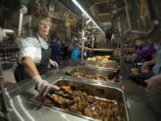 Kitchen manager Connie Lane, left, helps students load up their plates with chicken and other items made from local ingredients during a special lunch in honor of Taste Washington Day at Union Ridge Elementary School.