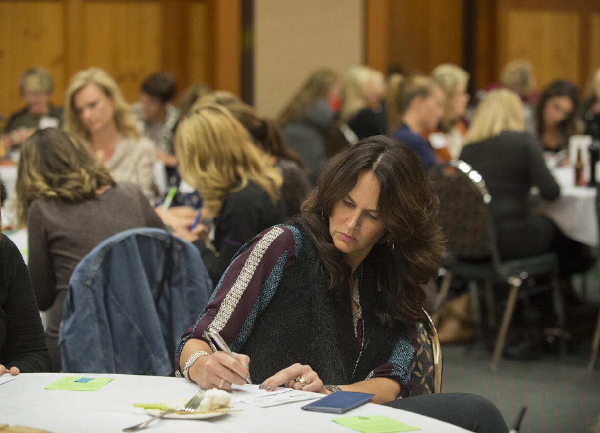 Janna Moats writes a check Monday to nonprofit Friends of the Children during the first meeting of 100 Women Who Care of SW Washington at The Heathman Lodge in Vancouver.