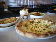 The cheesy baked polenta, clockwise from left, a Campfire sundae, a mixed greens salad and the Tocco di Verde pizza are served at Rally Pizza in Vancouver.