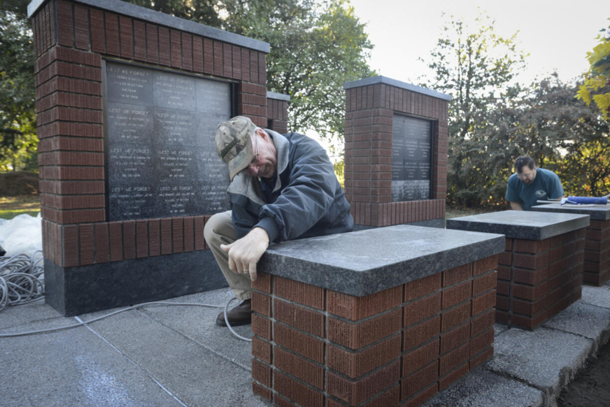 Harry Shook, left, applies weather stripping Tuesday to a section of the Clark County Vietnam Memorial in preparation for Saturday&#039;s dedication ceremony while John Hoefer seals concrete.