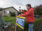 Democratic state Senate candidate Tim Probst sets up a lawn sign outside the home of a voter in northeast Vancouver on Friday.